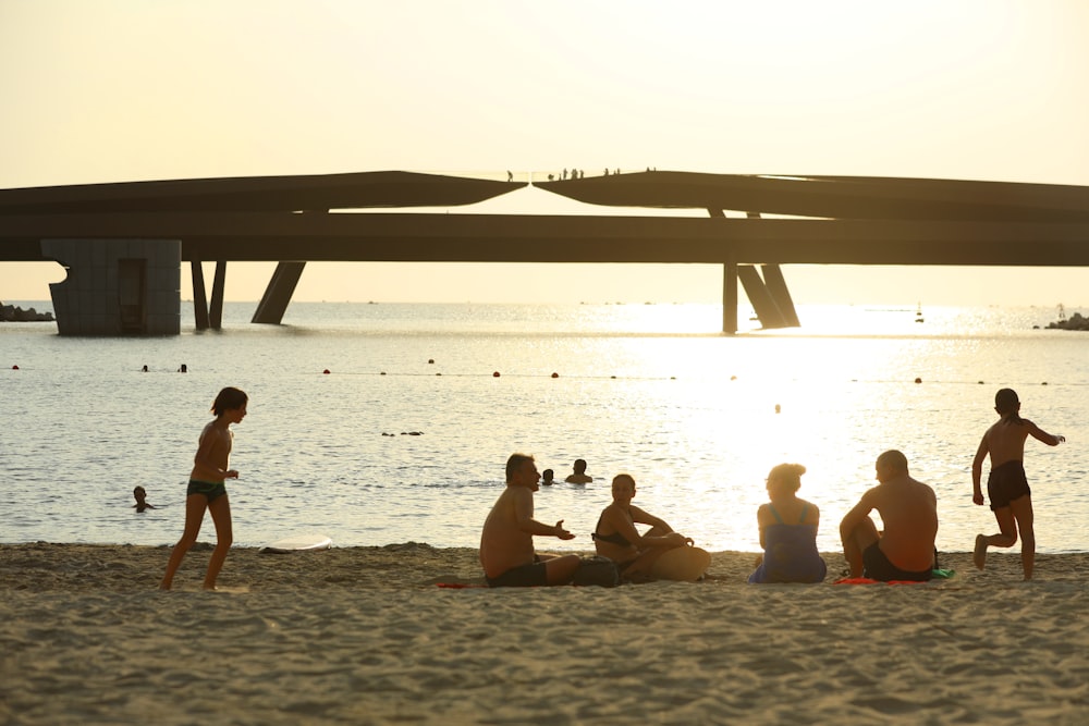 a group of people sitting on top of a sandy beach