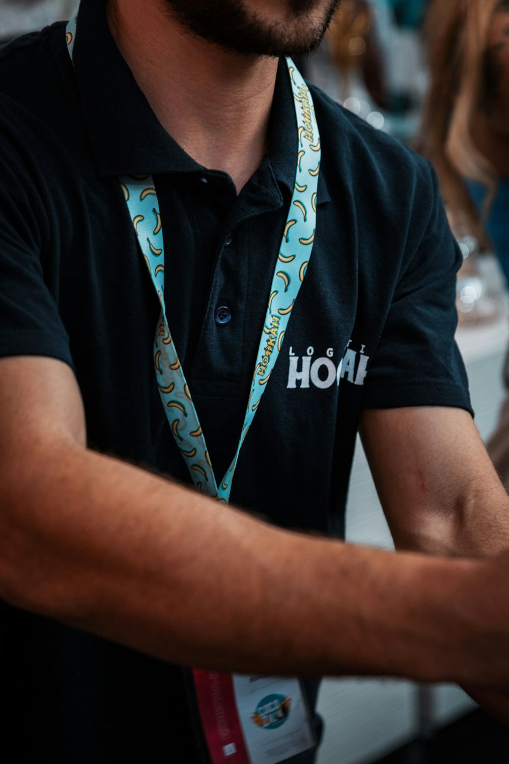 a man wearing a black shirt and a blue lanyard around his neck