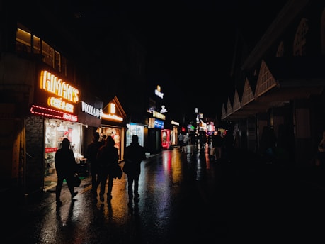 a group of people walking down a street at night