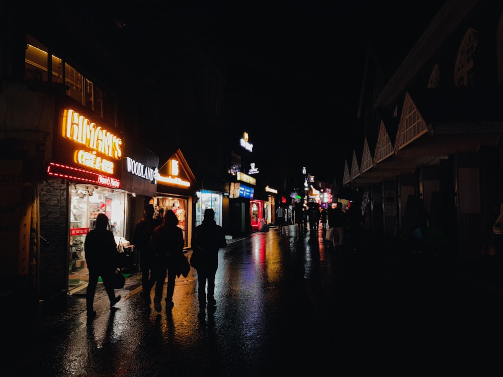 a group of people walking down a street at night