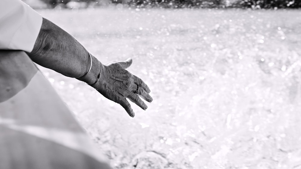 a person's hand reaching out of the water