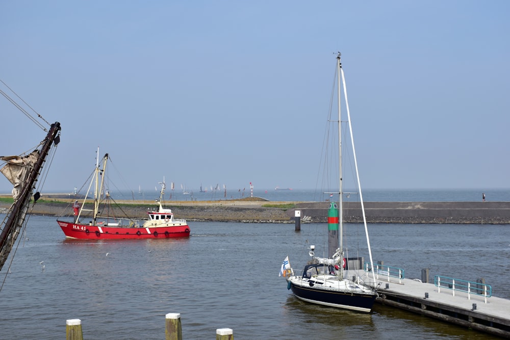 a red boat in the water next to a dock