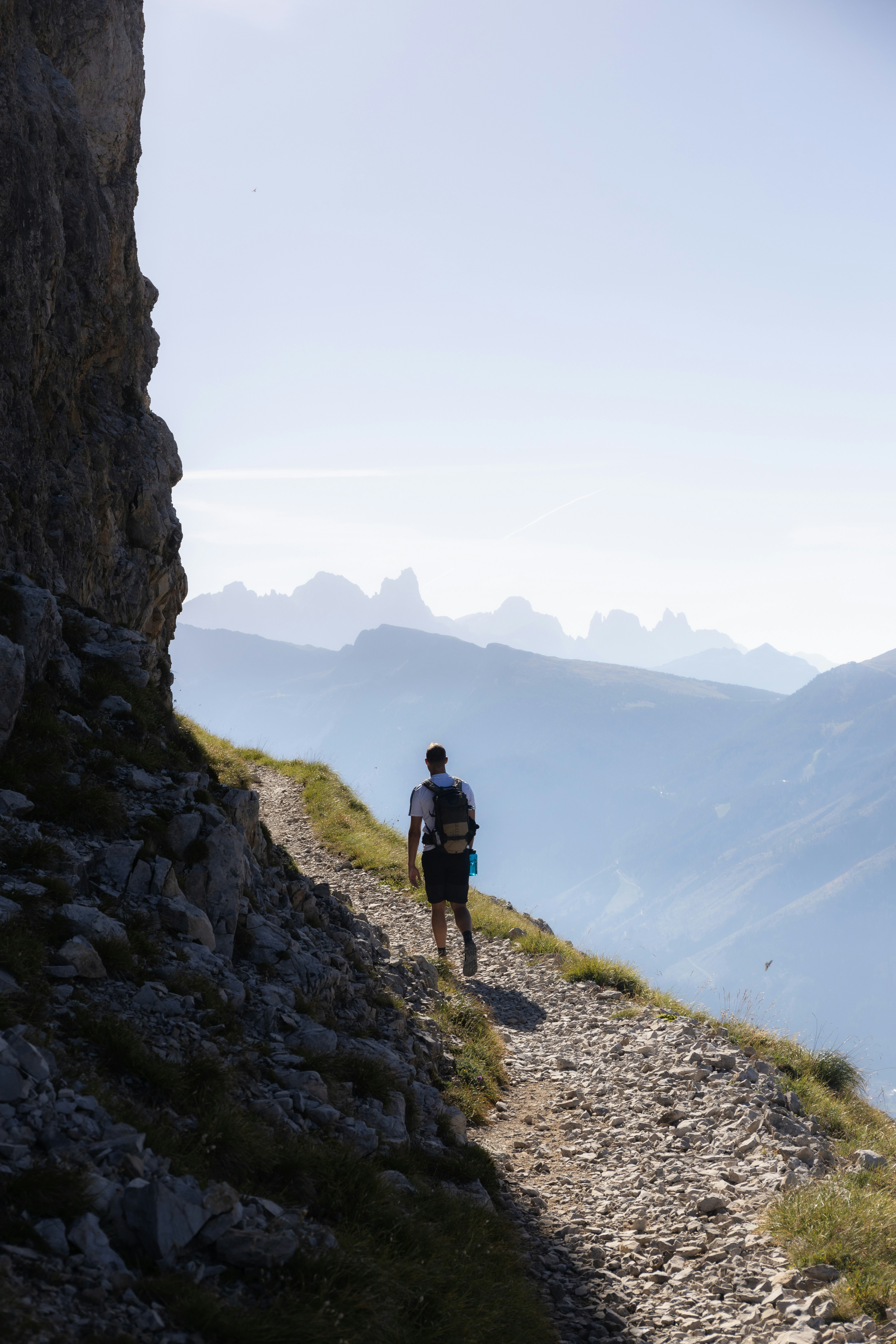 a man hiking up a rocky trail in the mountains