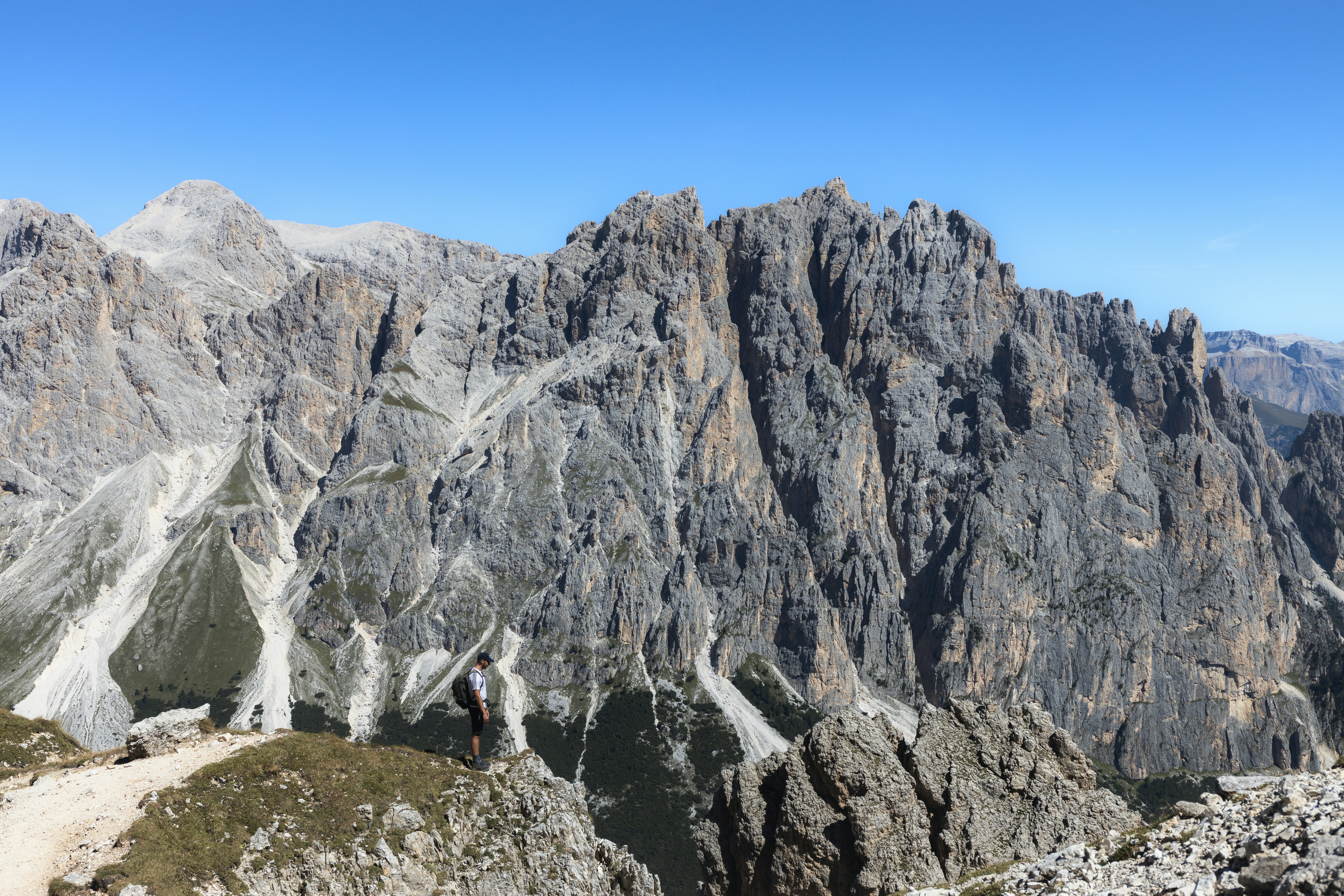 a man standing on top of a mountain next to a lush green forest