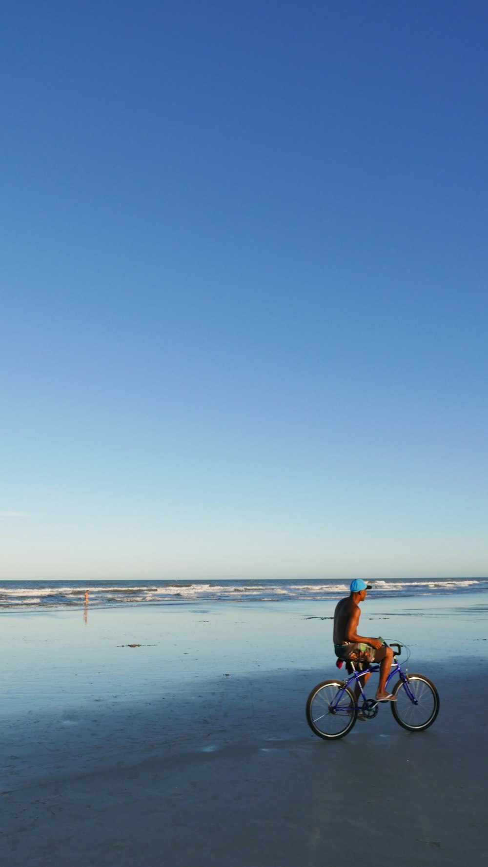 a man riding a bike on a beach next to the ocean