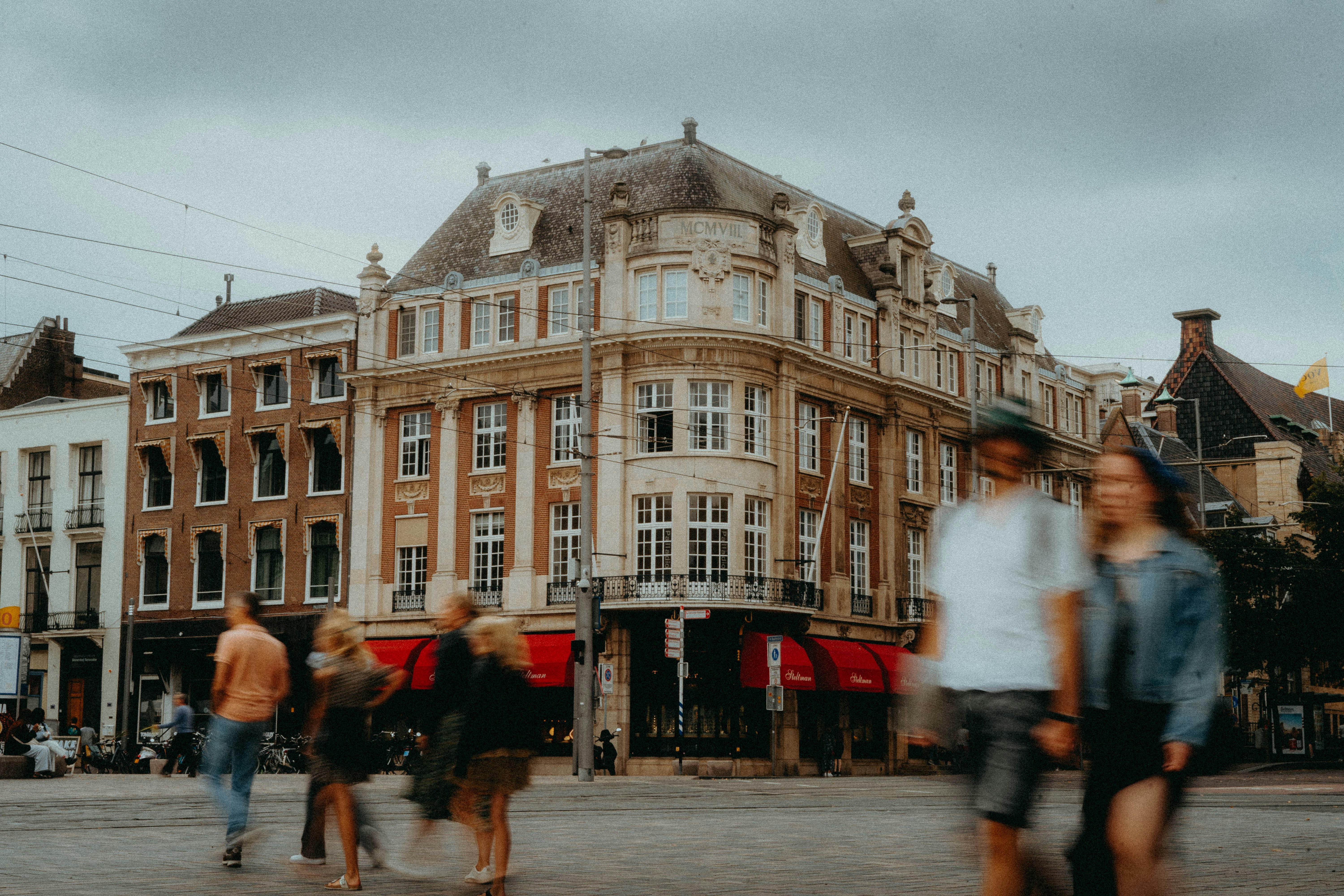 a group of people walking down a street next to tall buildings