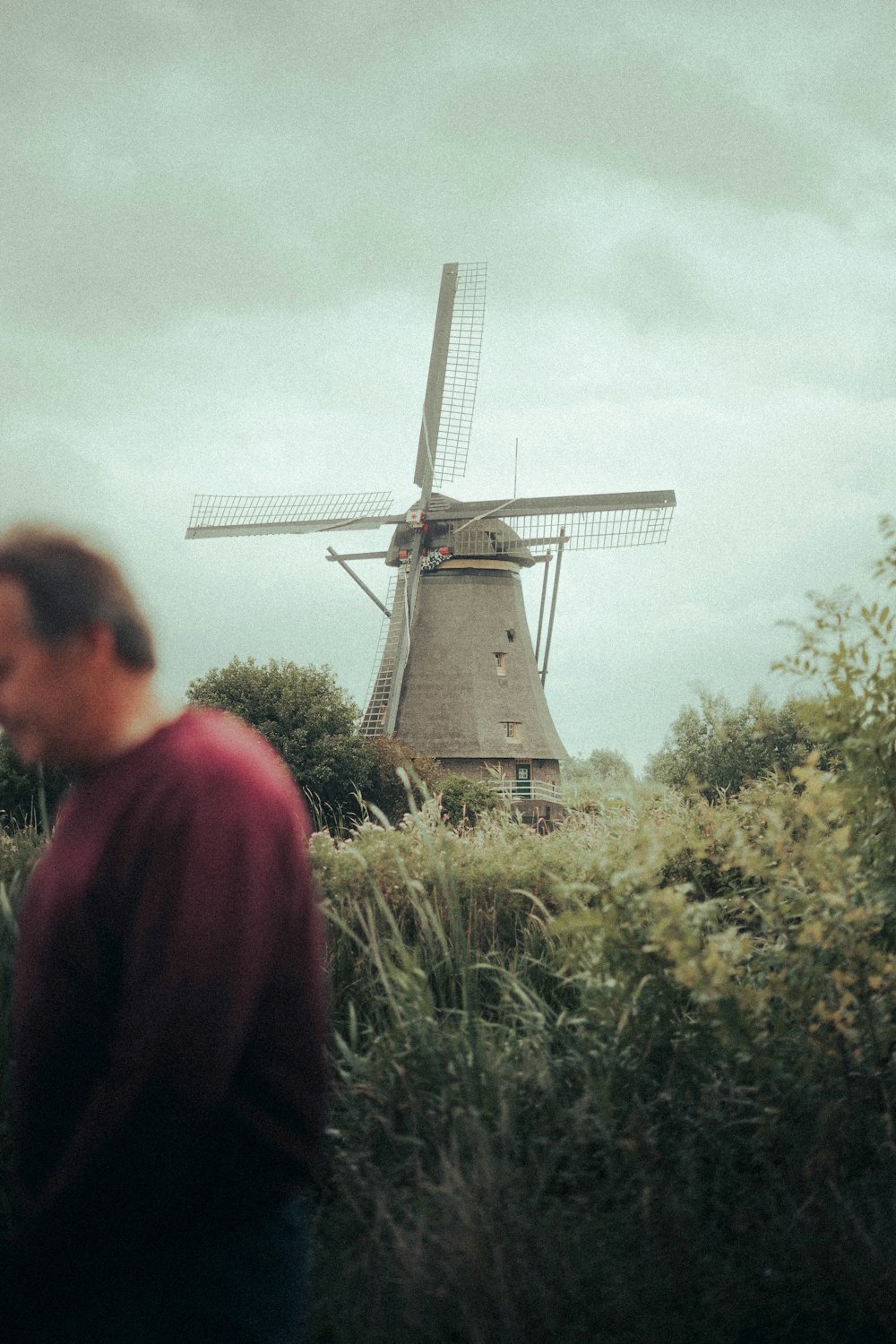 a man standing in a field next to a windmill