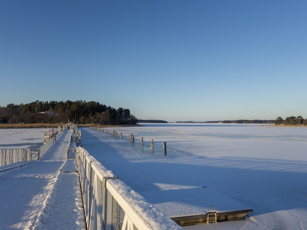 a snow covered walkway next to a frozen lake