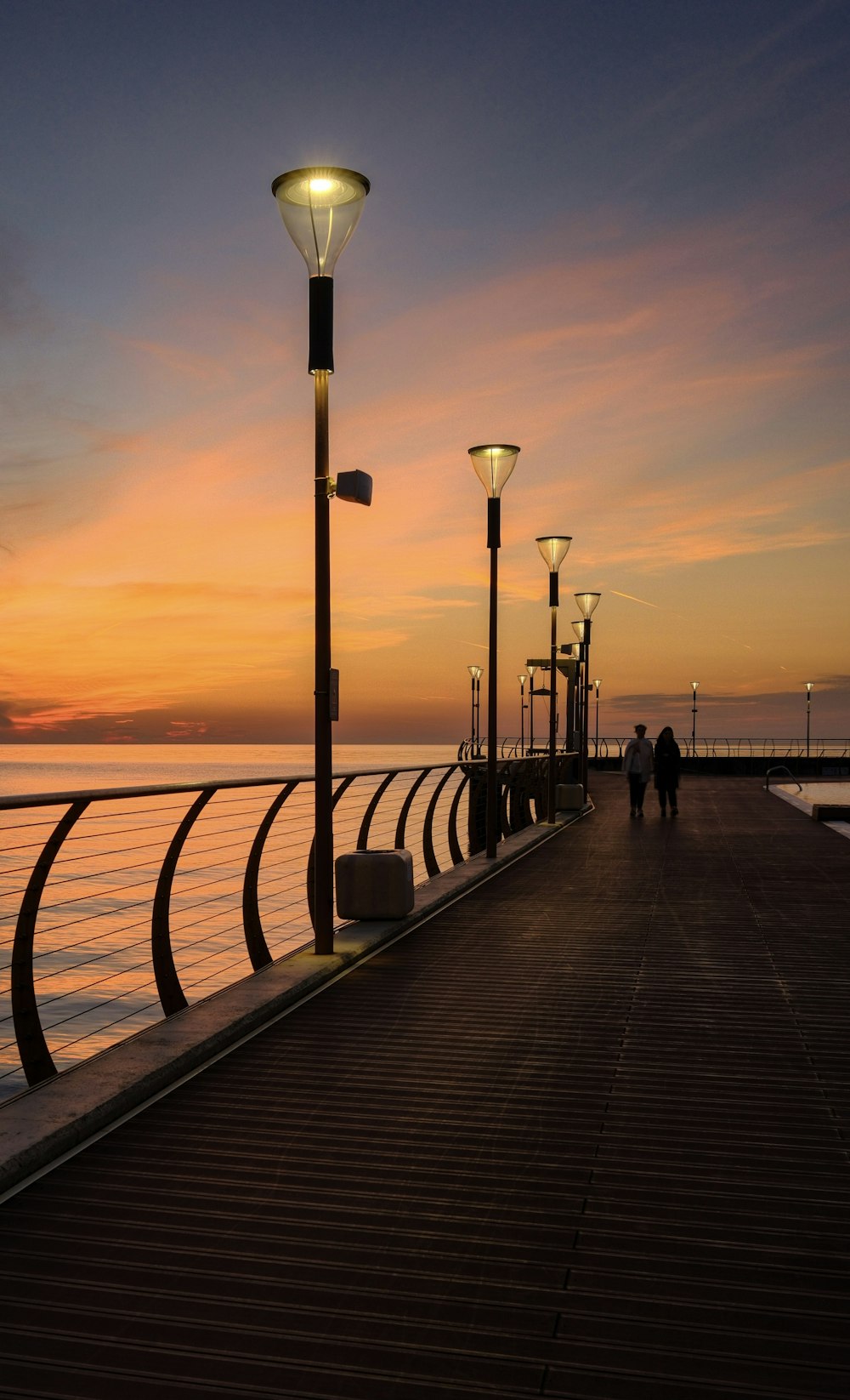 a pier at sunset with people walking on it
