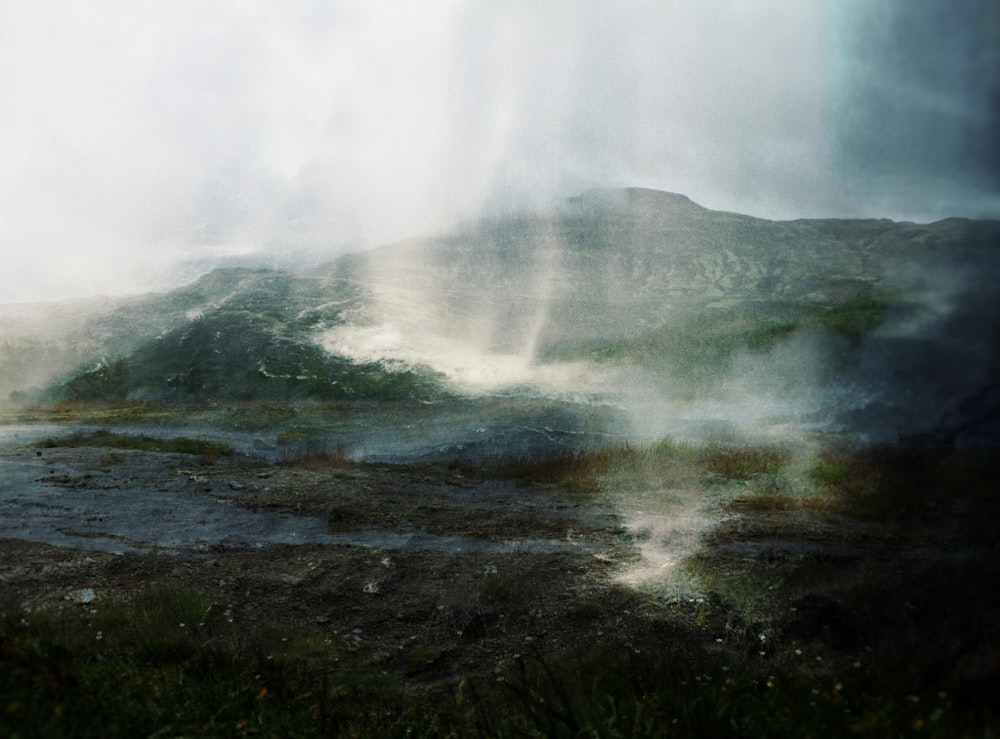 a mountain covered in steam and steam rising from the ground