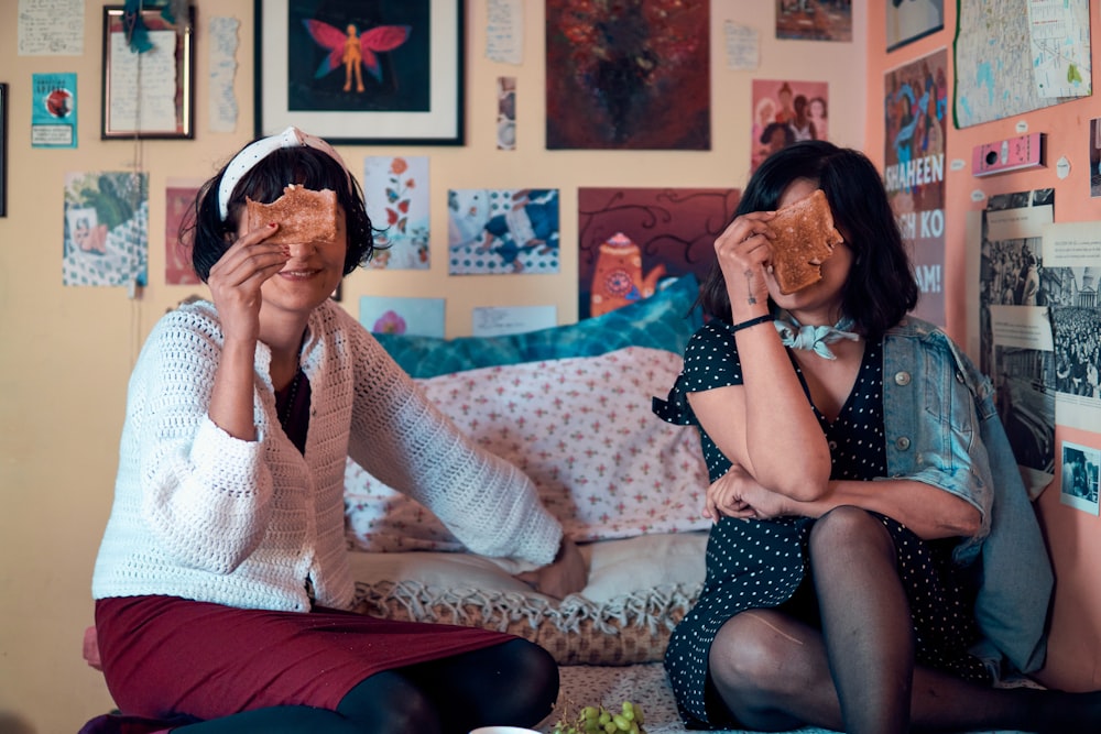 a couple of women sitting on top of a couch