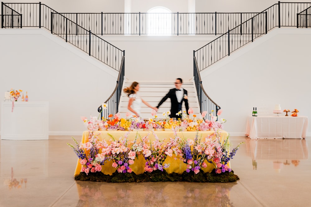 a man and a woman standing in front of a table with flowers on it