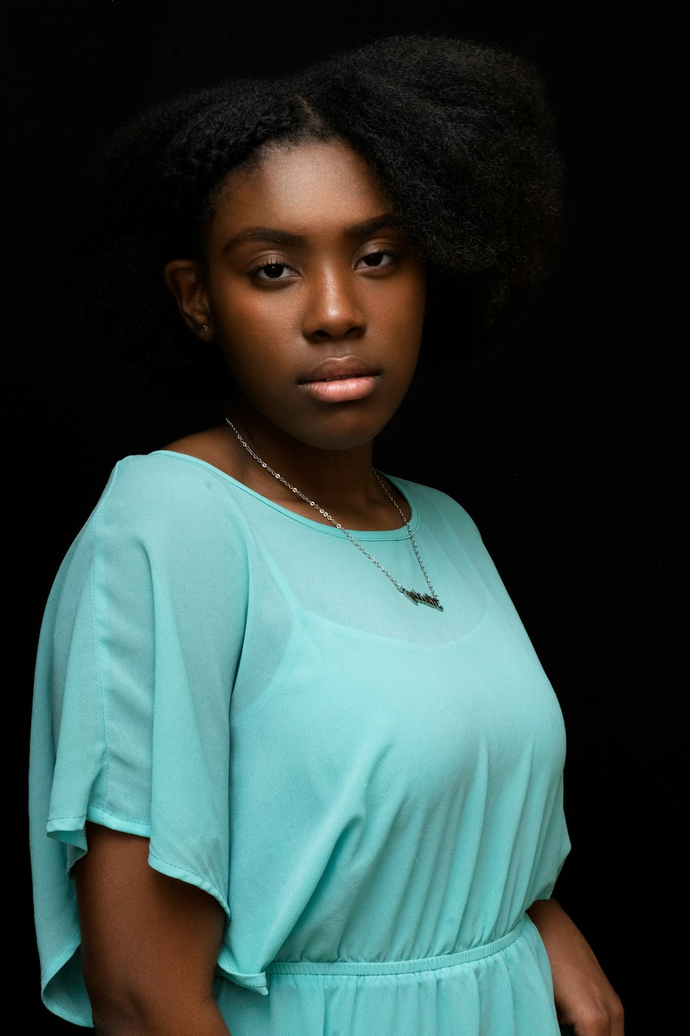 a woman with an afro standing in front of a black background