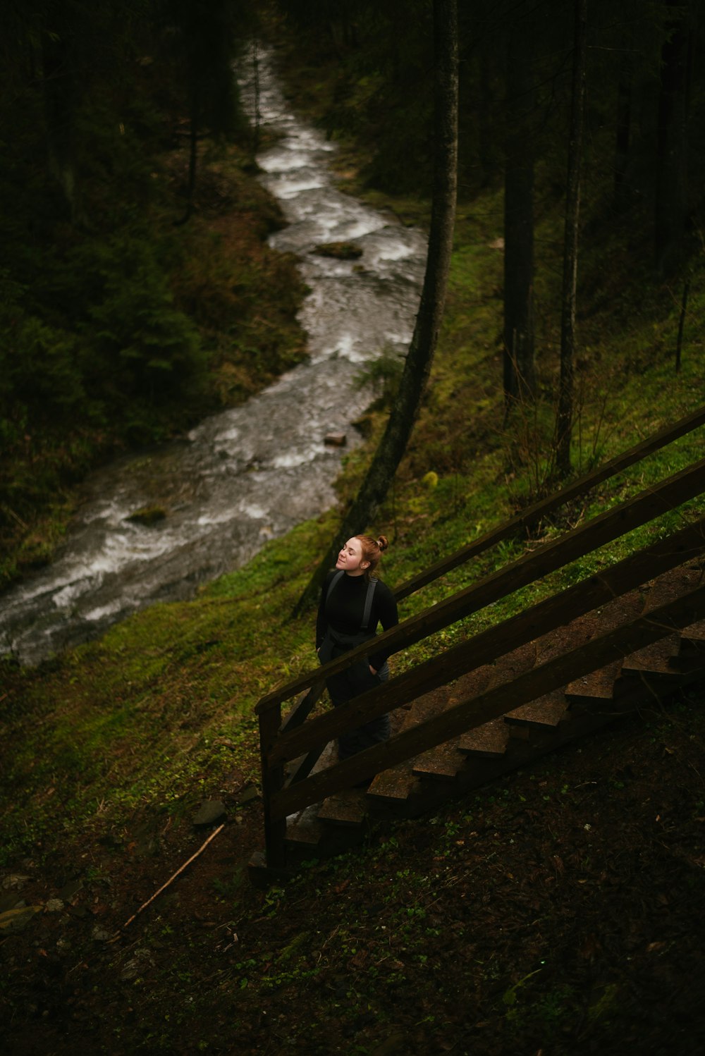 a man sitting on a wooden bench next to a river