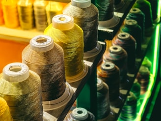 a row of spools of thread sitting on top of a shelf