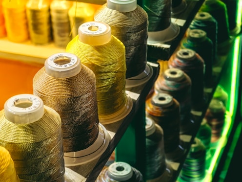a row of spools of thread sitting on top of a shelf