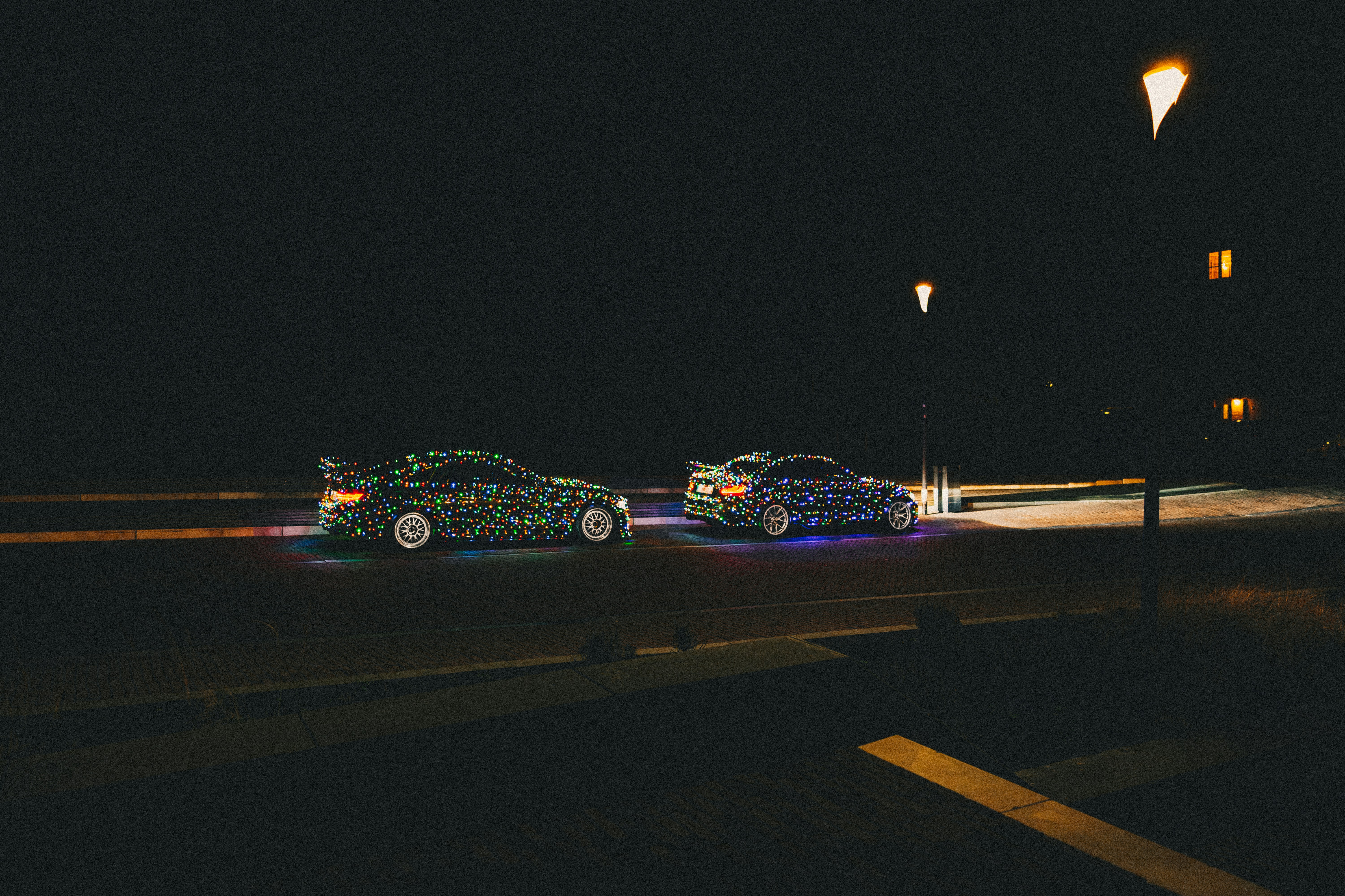 a couple of cars driving down a street at night