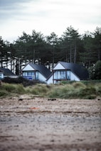 a couple of houses sitting on top of a sandy beach