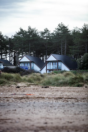 a couple of houses sitting on top of a sandy beach