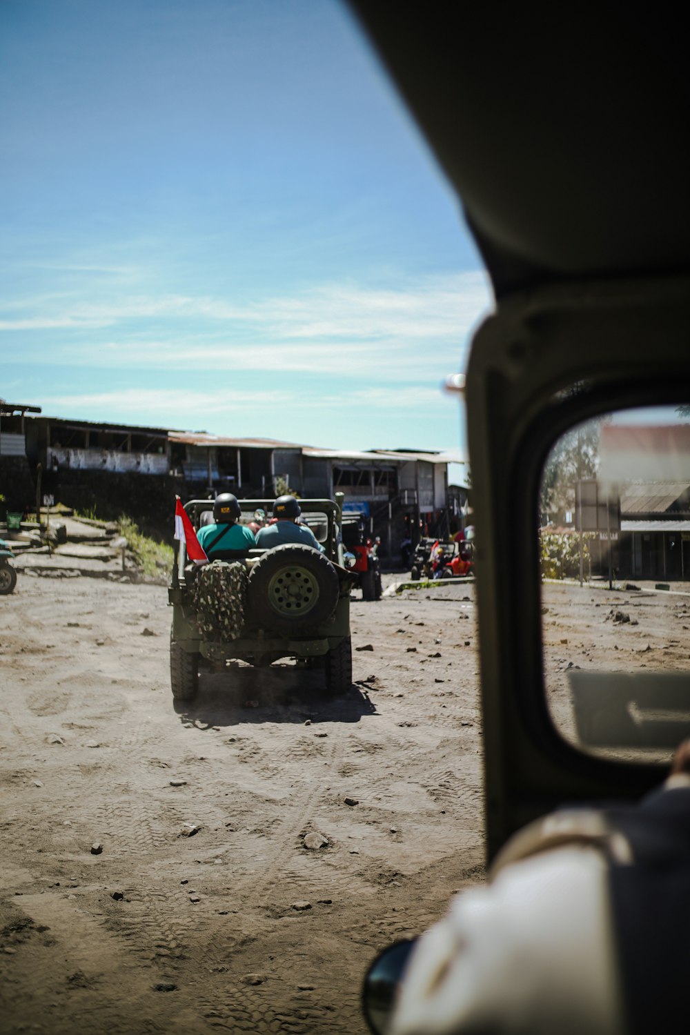 a jeep driving down a dirt road next to a building