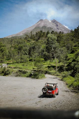 a small car parked on a dirt road in front of a mountain