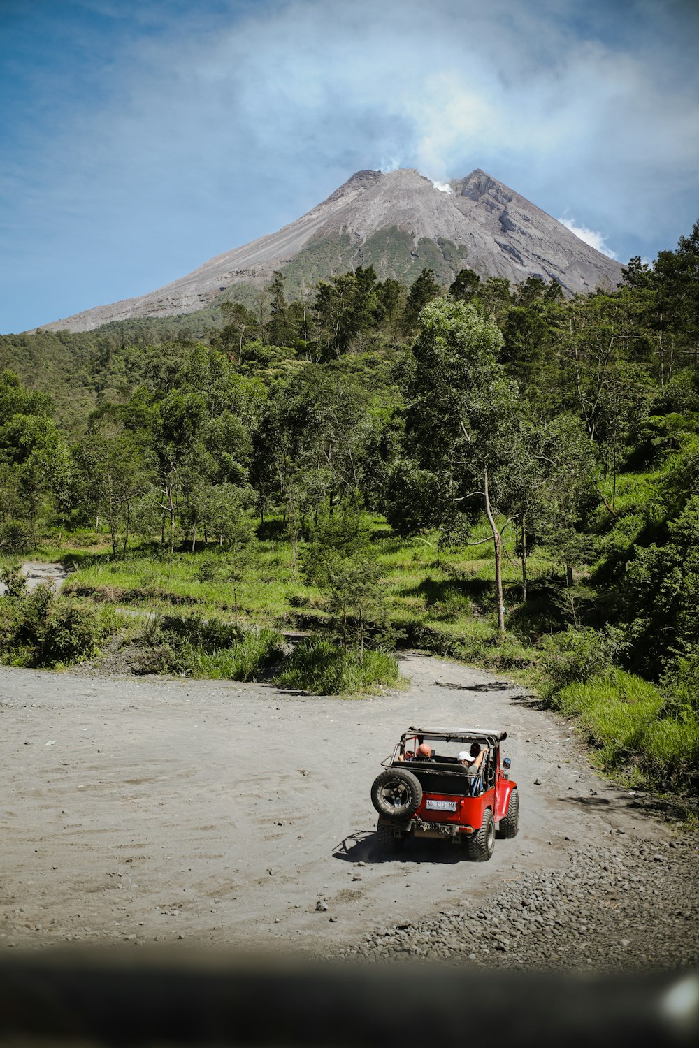 um pequeno carro estacionado em uma estrada de terra em frente a uma montanha