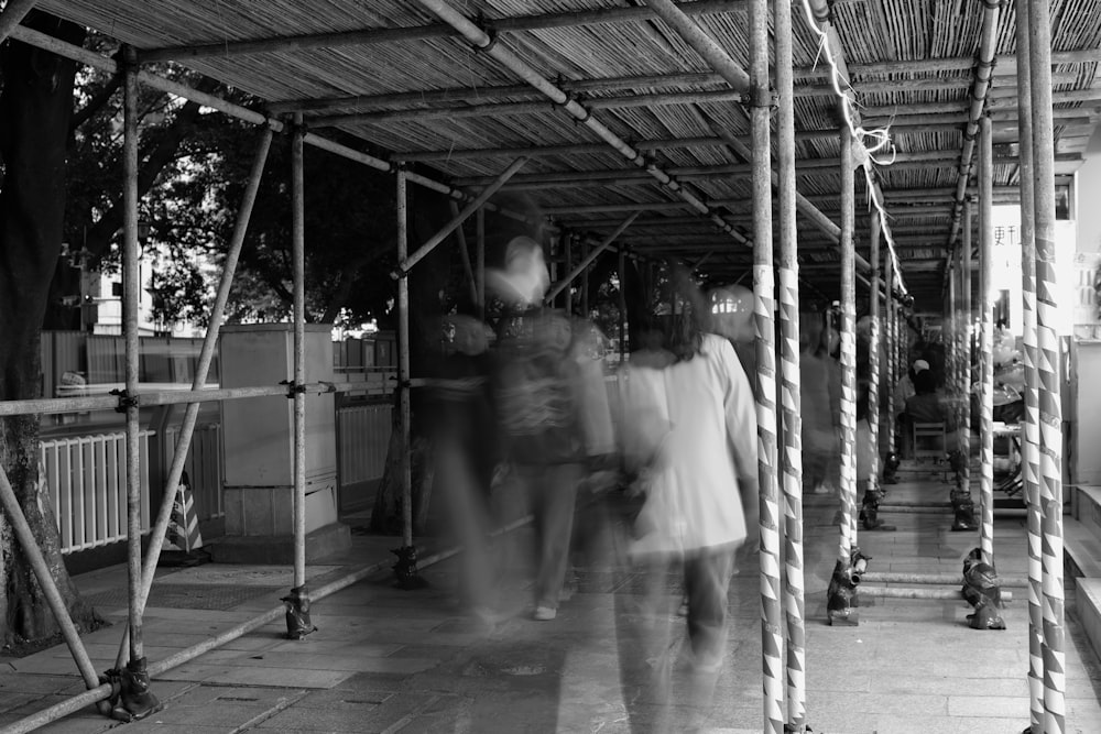 a group of people walking down a sidewalk under a roof