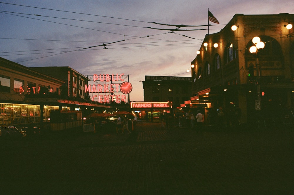 a city street at night with a neon sign in the background