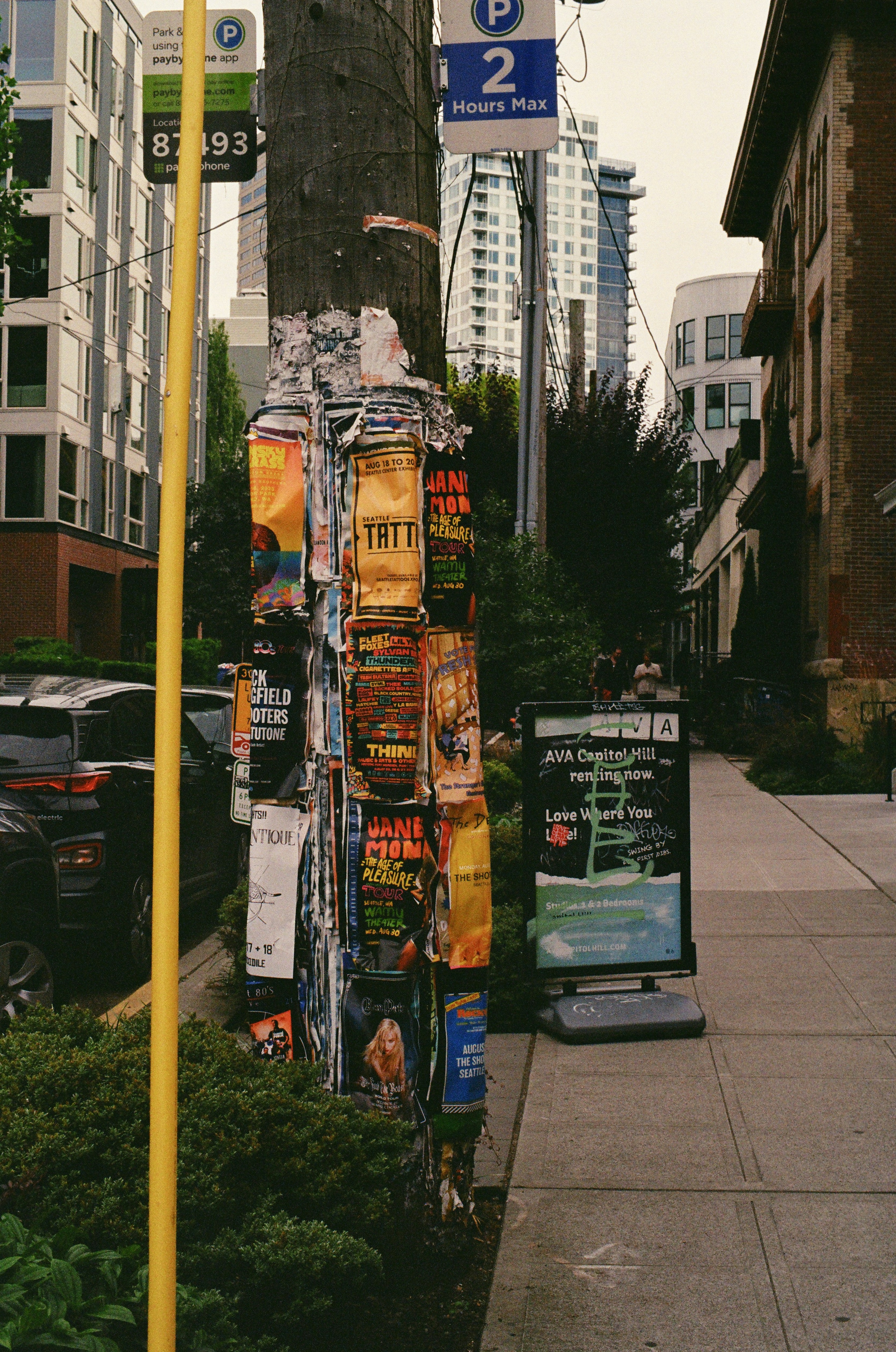 a street sign next to a sidewalk with posters on it