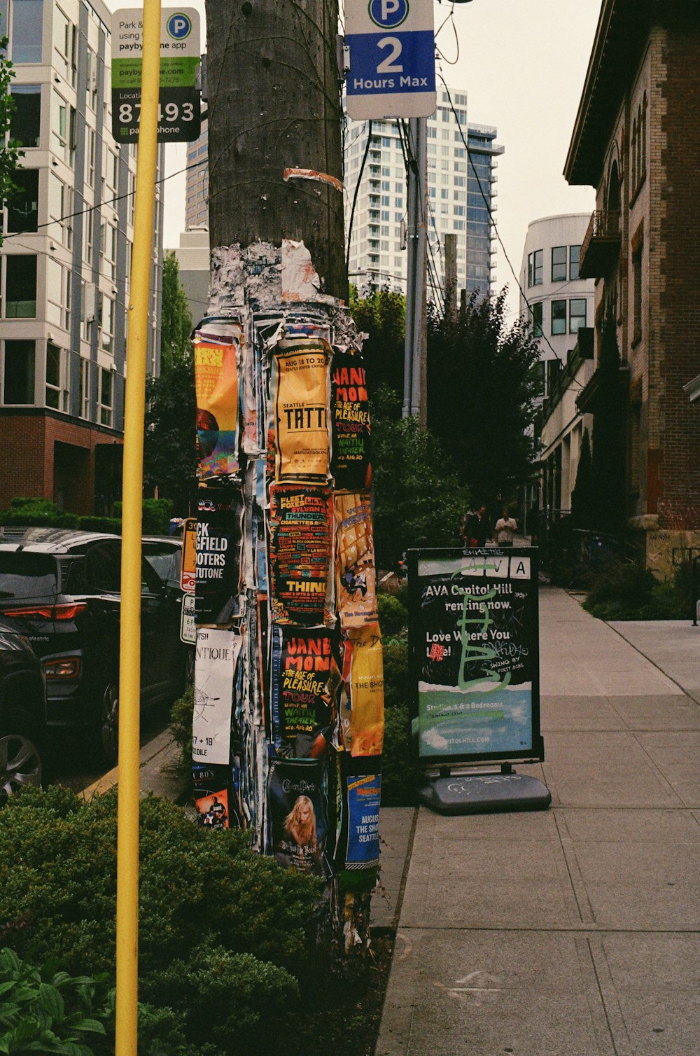 a street sign next to a sidewalk with posters on it