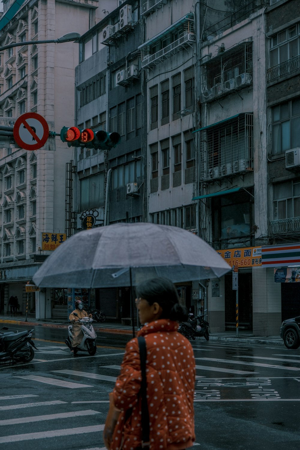 a woman walking across a street holding an umbrella