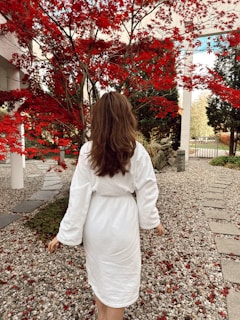 a woman in a white robe walking down a path