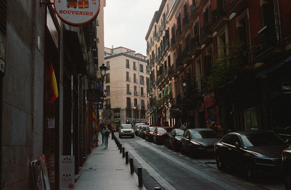 a city street lined with parked cars and tall buildings