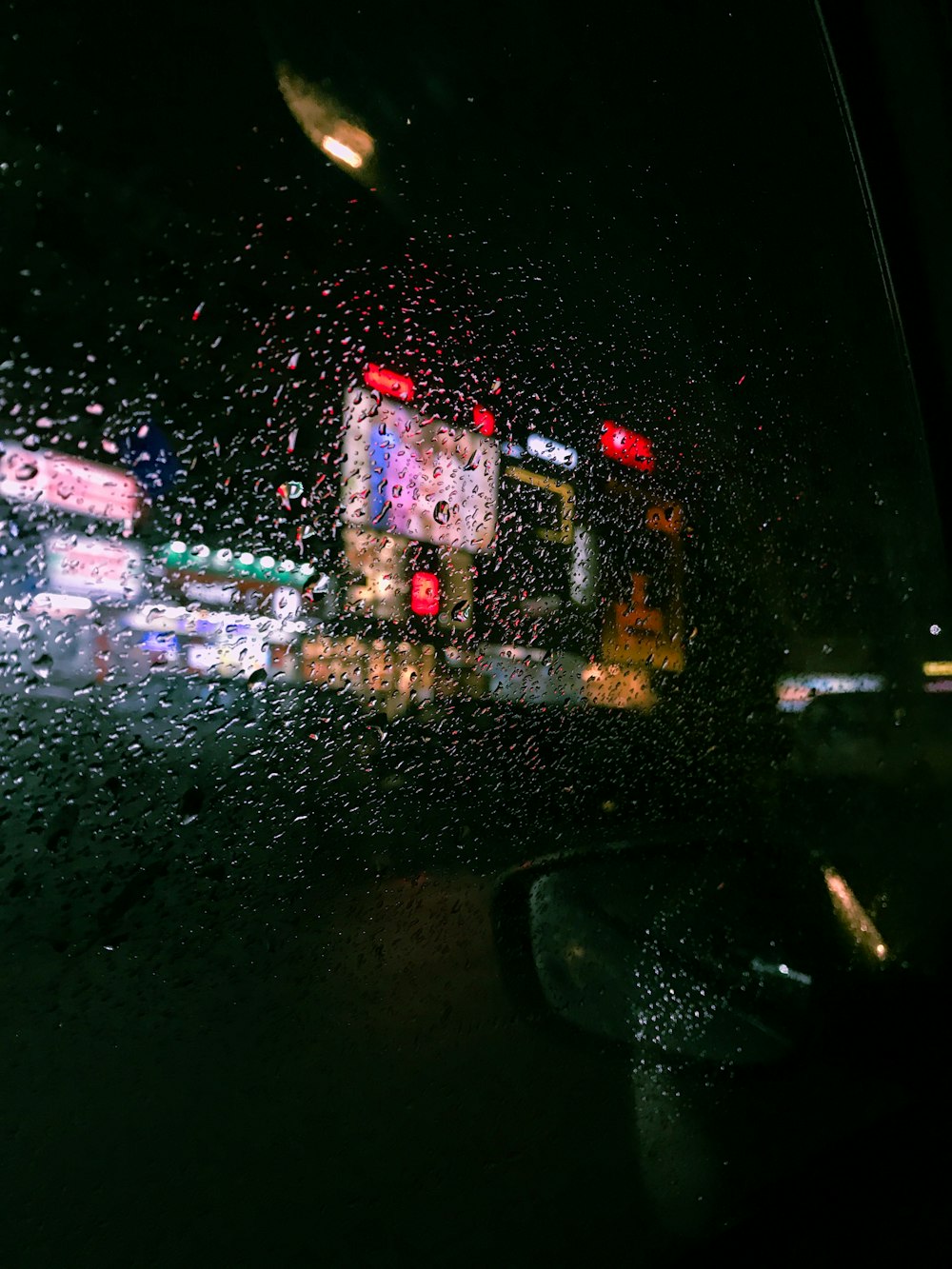 Una vista de una calle de la ciudad a través de un parabrisas cubierto de lluvia