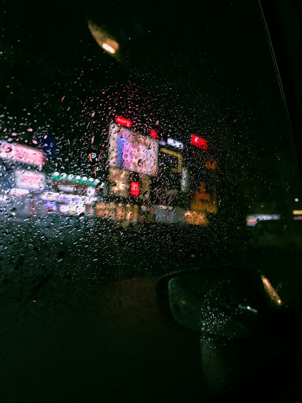 uma vista de uma rua da cidade através de um para-brisa coberto de chuva