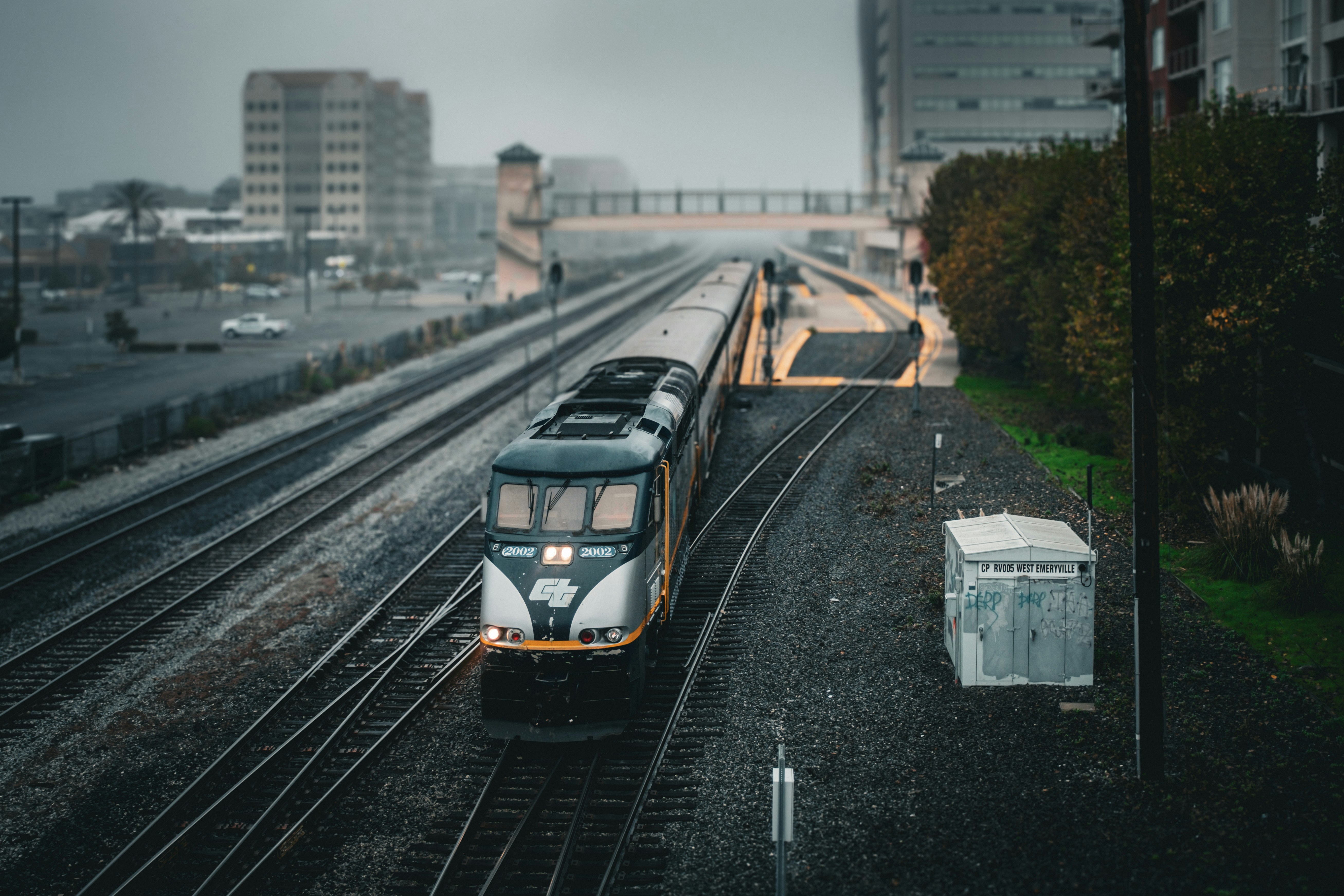 a train traveling down train tracks next to tall buildings, 