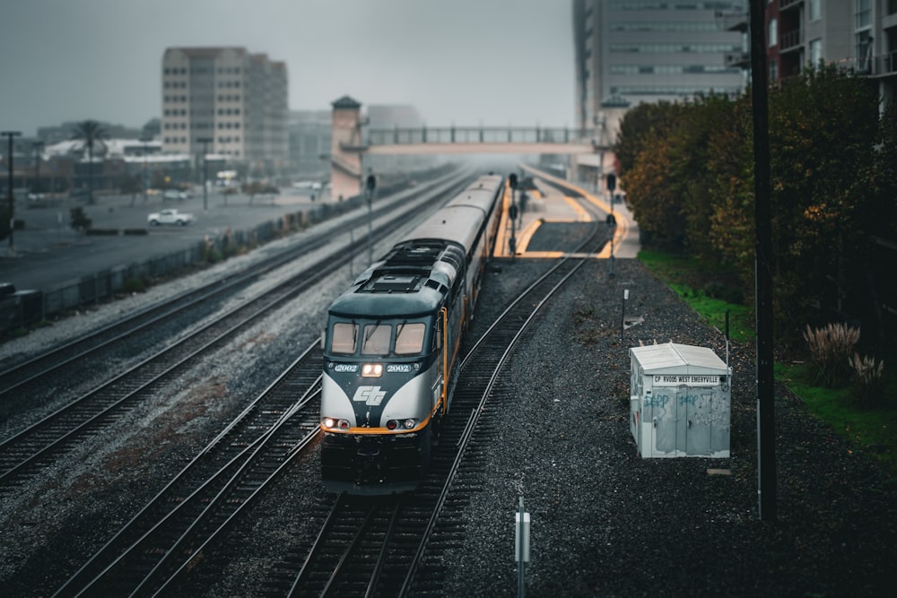 Un tren que viaja por las vías del tren junto a edificios altos