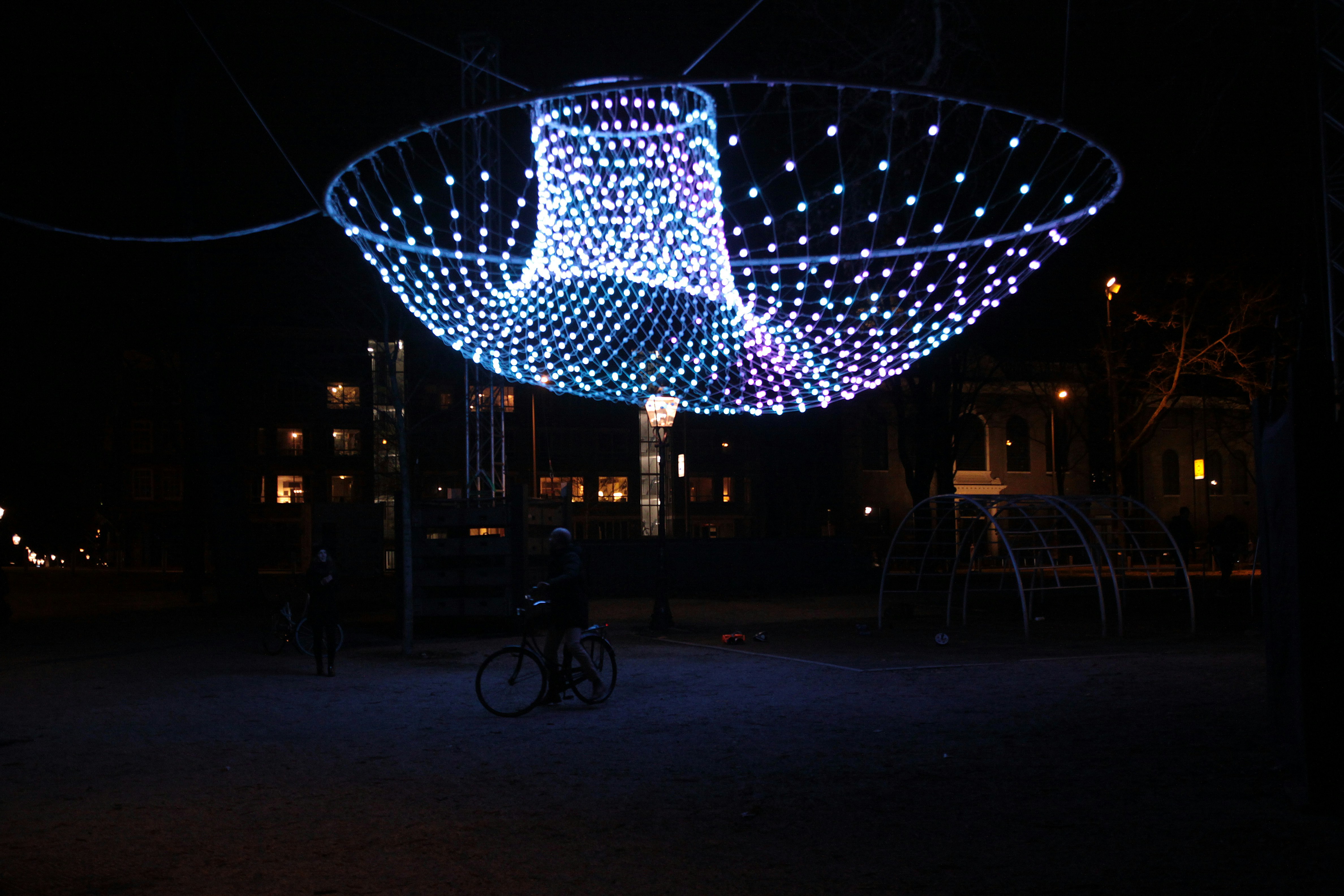 a person riding a bike under a lit up structure