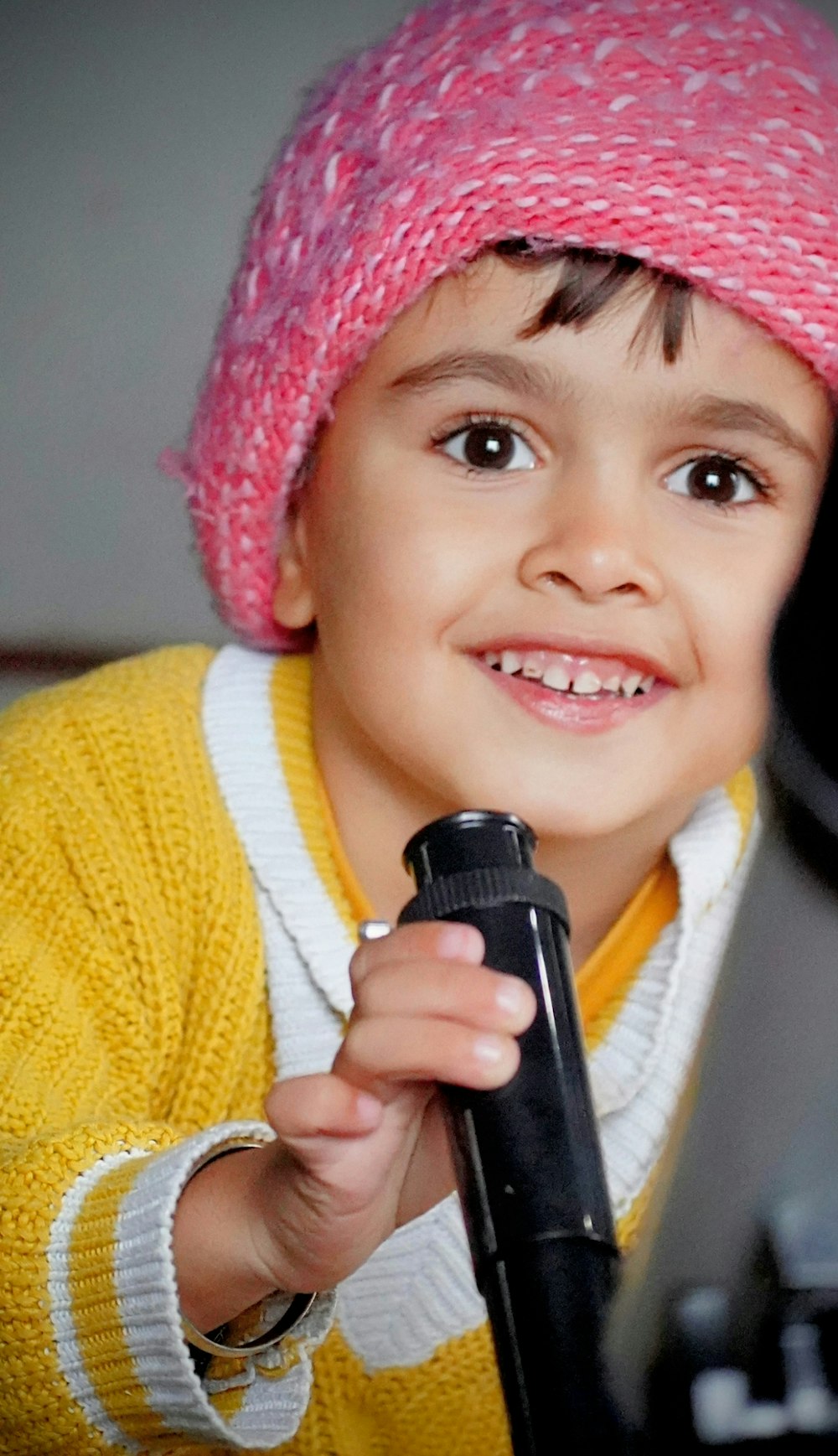 a young boy wearing a pink hat holding a microphone