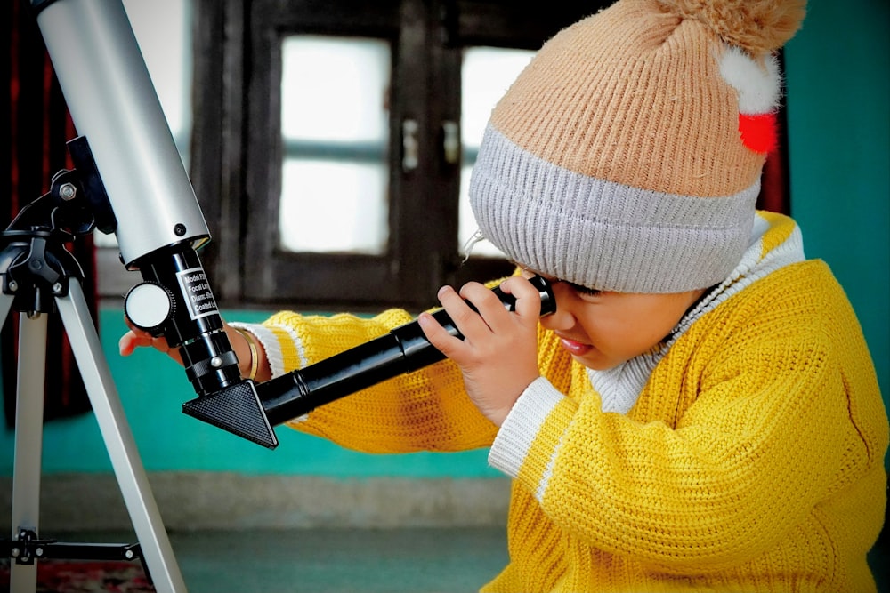 a young boy is looking through a telescope