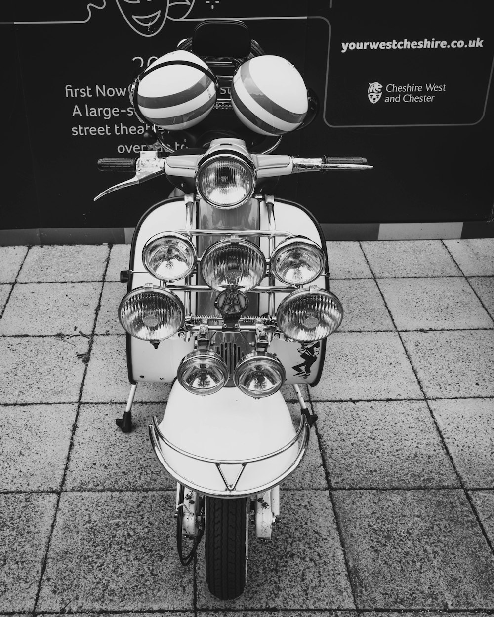 a scooter is parked on a sidewalk near a sign