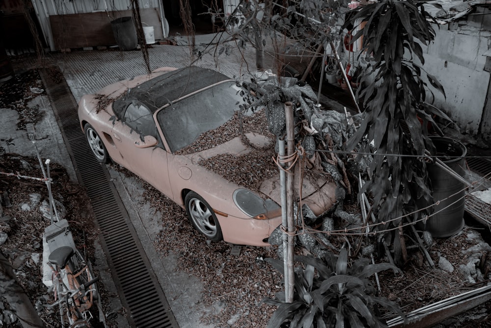 a pink car parked in a yard next to a tree