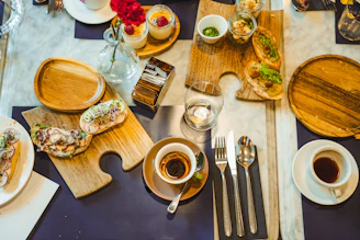 a table topped with plates of food and cups of coffee