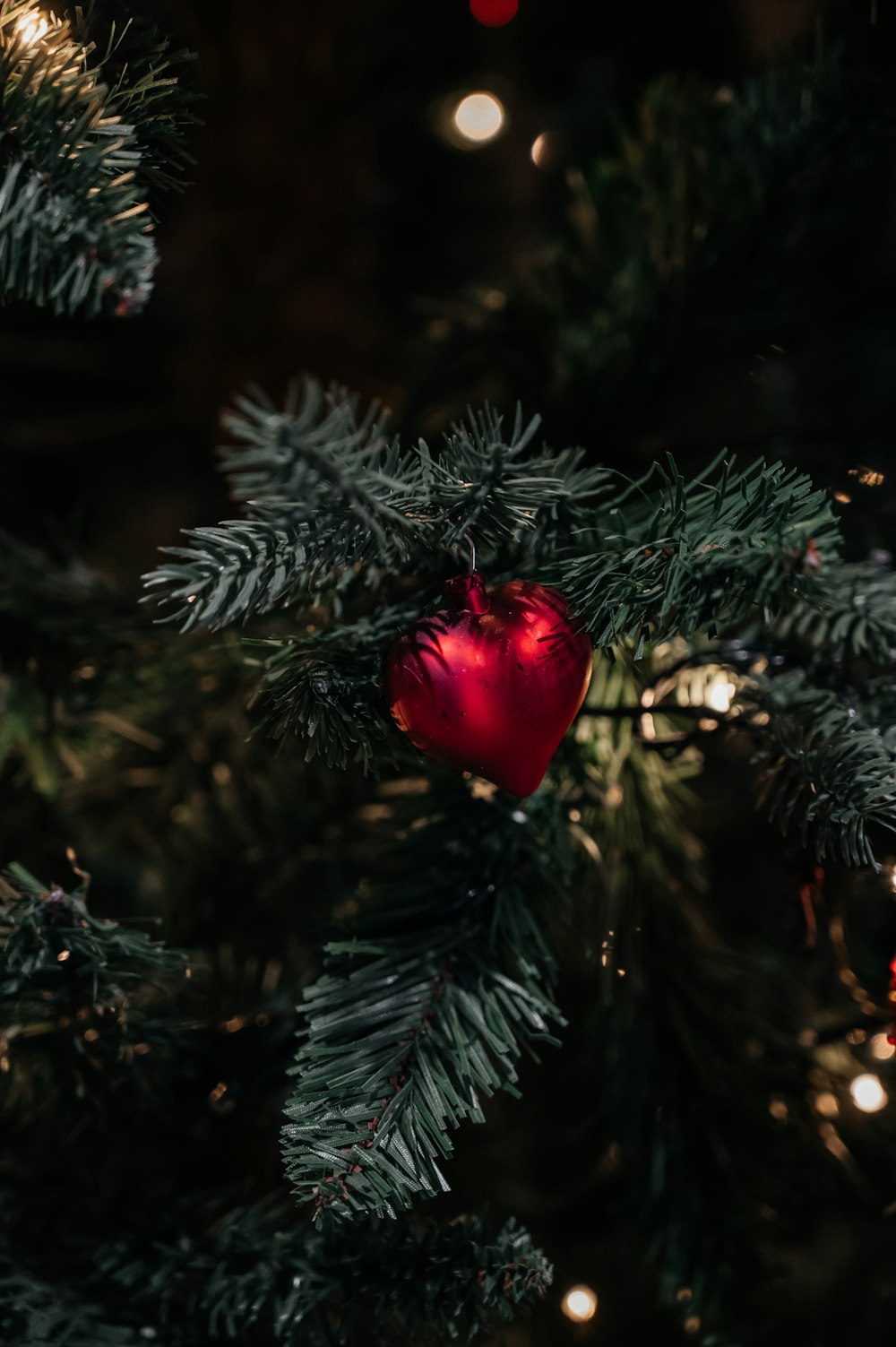 ein rotes Ornament, das an einem Weihnachtsbaum hängt