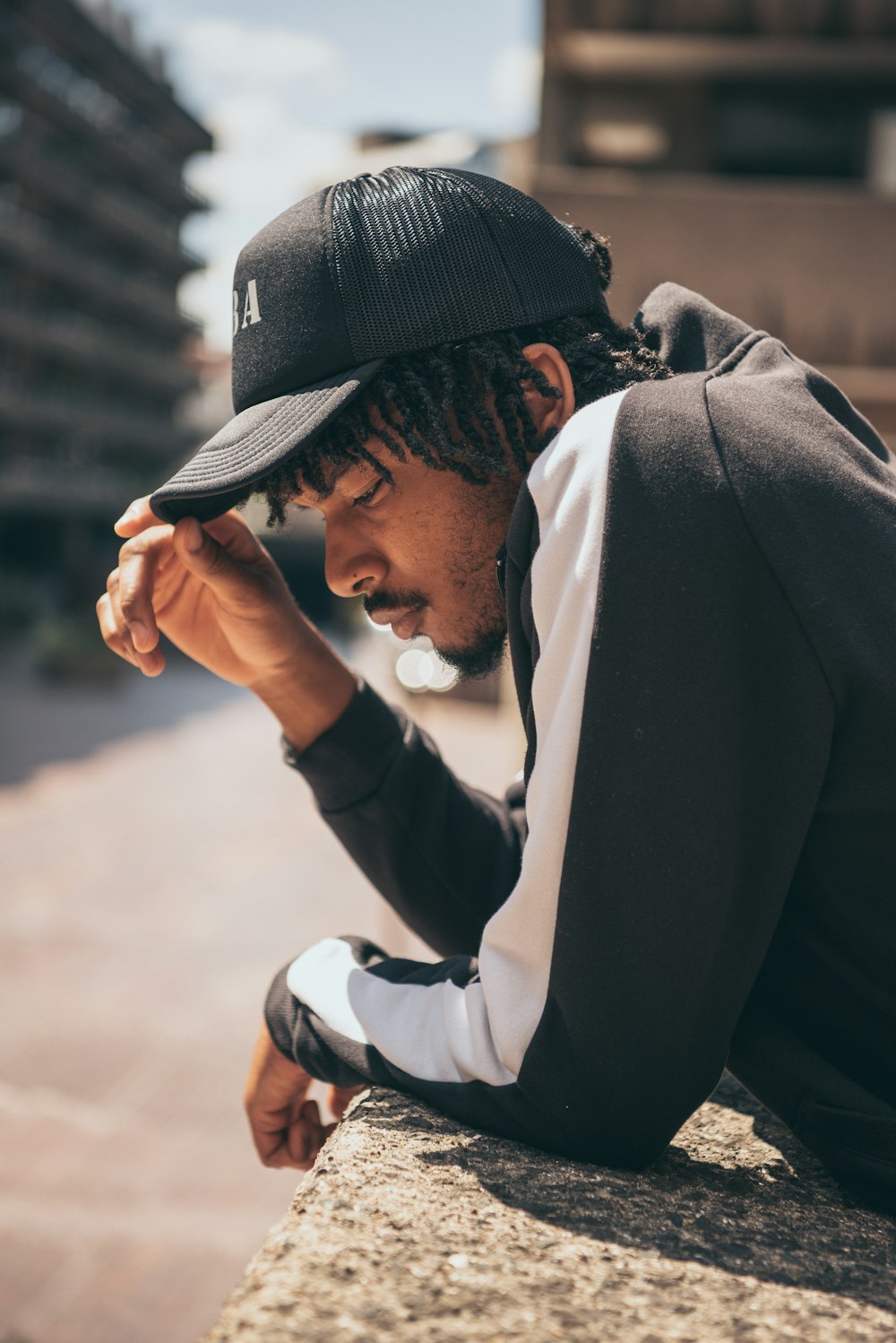 a man with dreadlocks sitting on a ledge