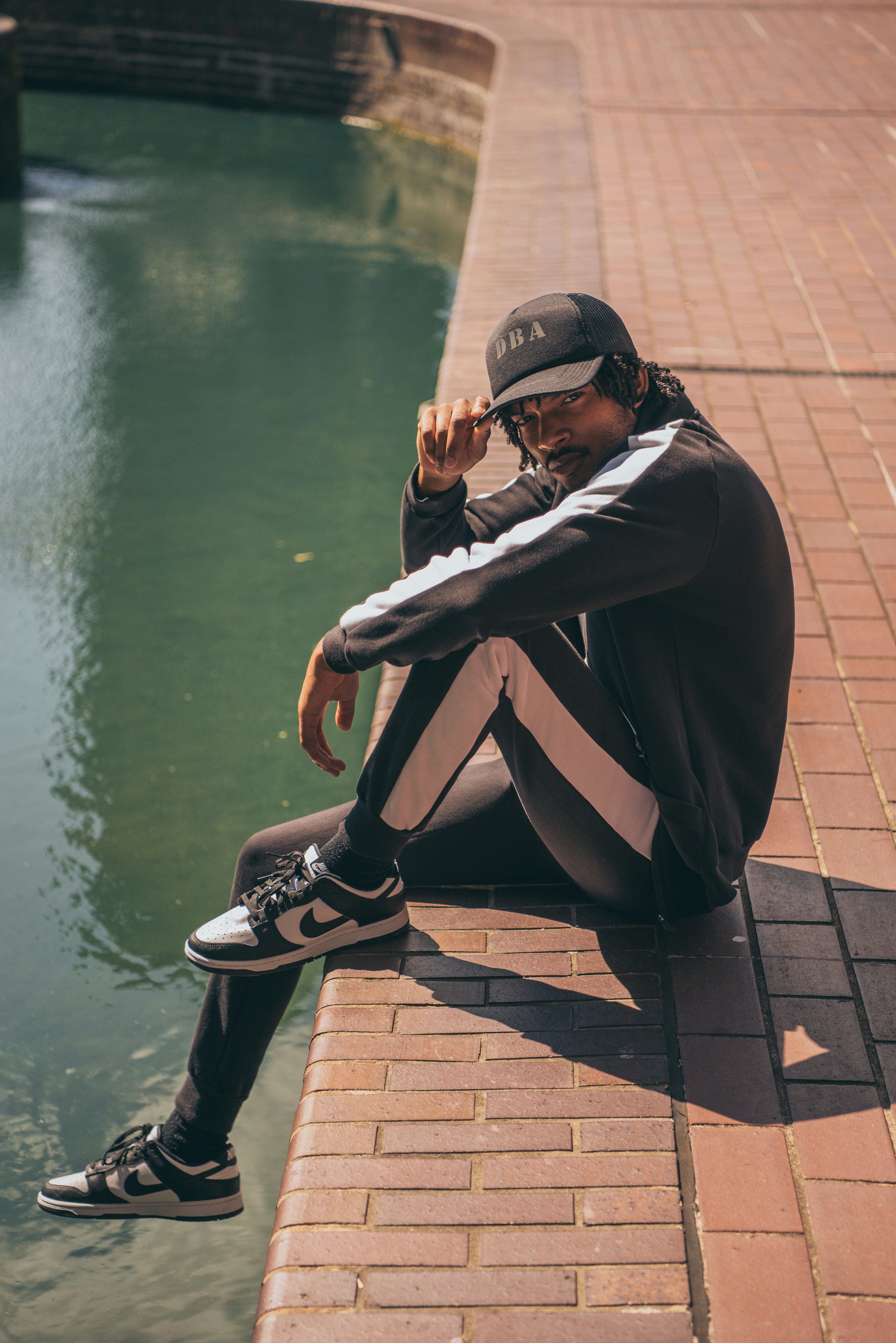 a man sitting on a brick wall next to a body of water