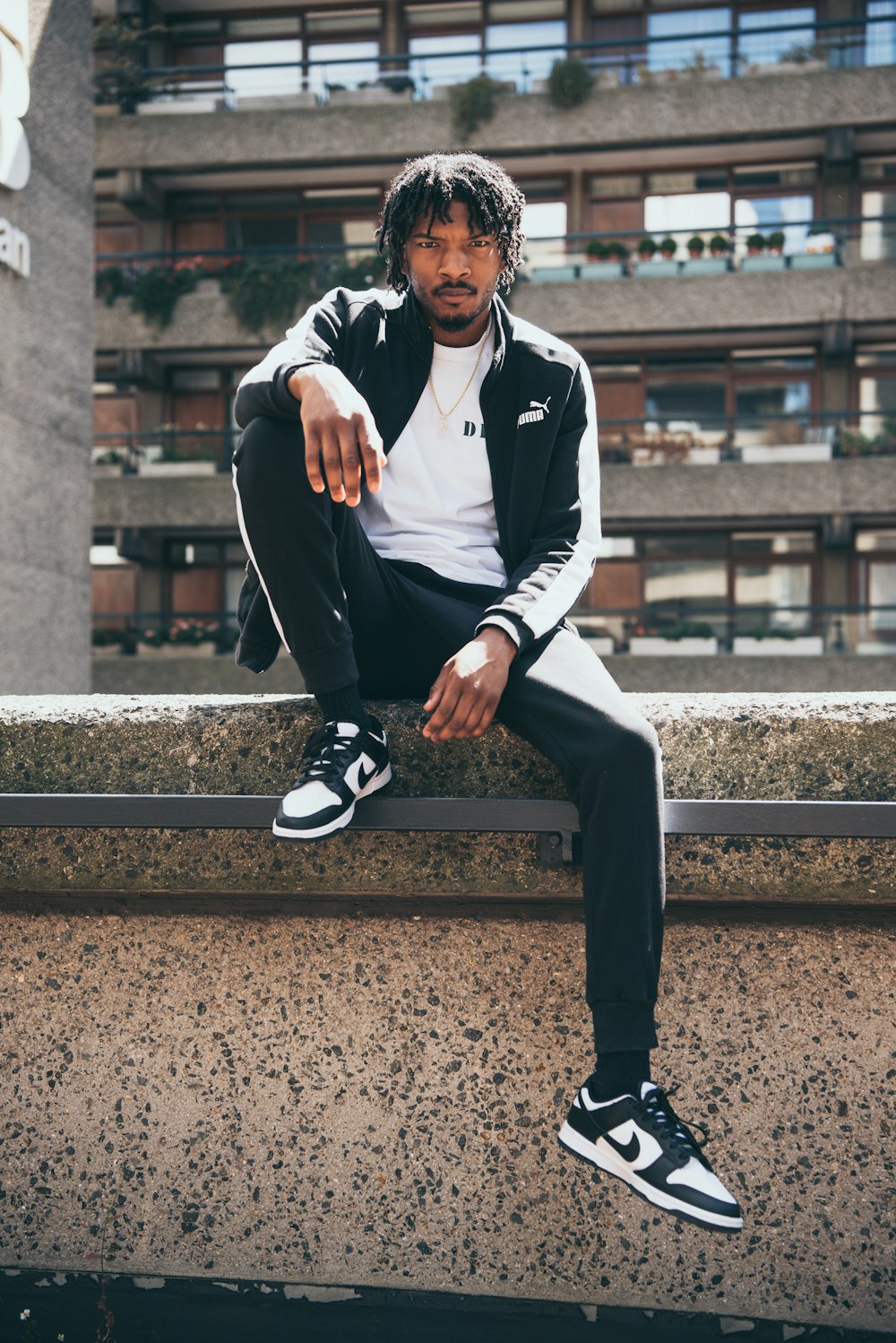 a man sitting on a ledge in front of a building