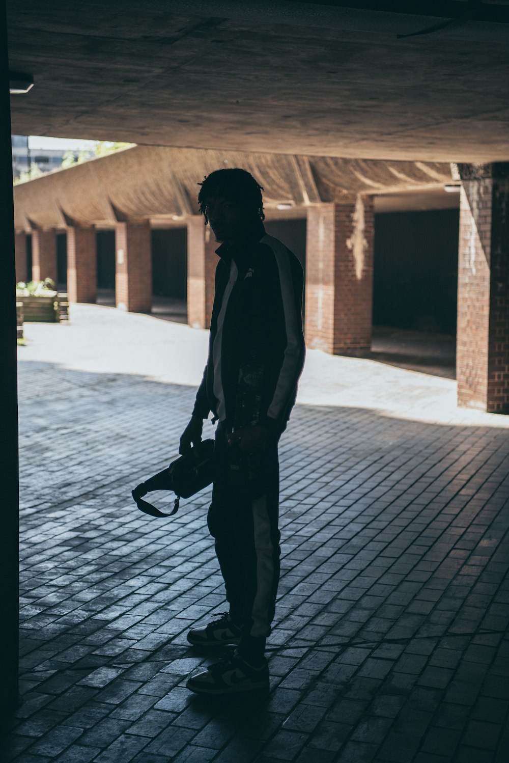 a man holding a skateboard in a parking garage