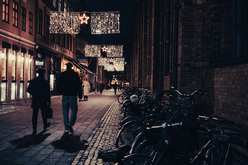 a couple of people walking down a street at night