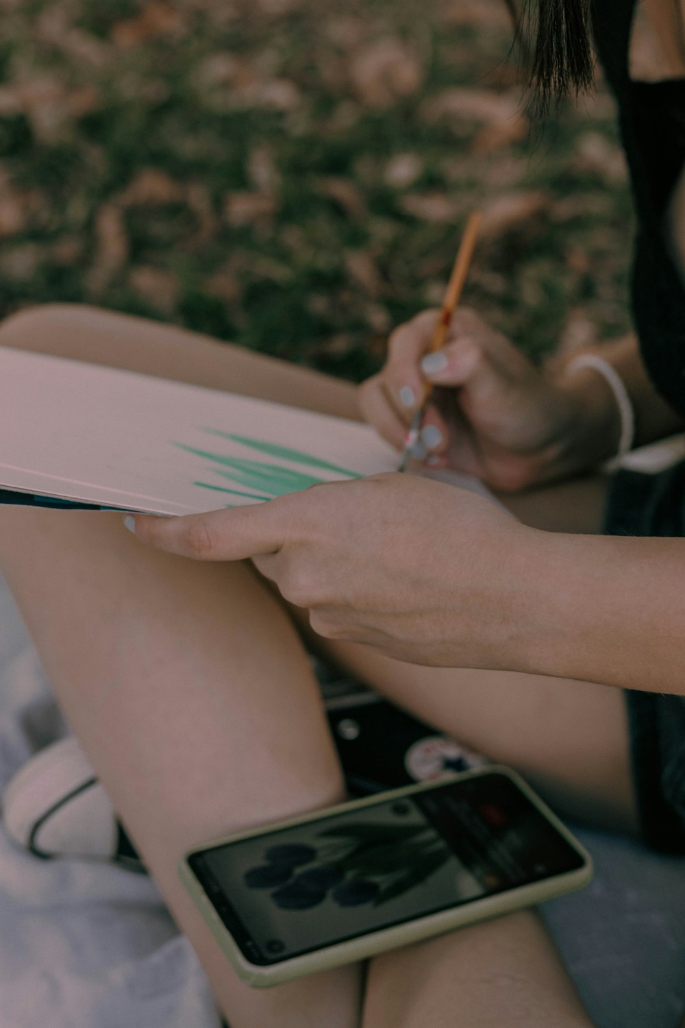 a woman sitting on the ground writing on a book